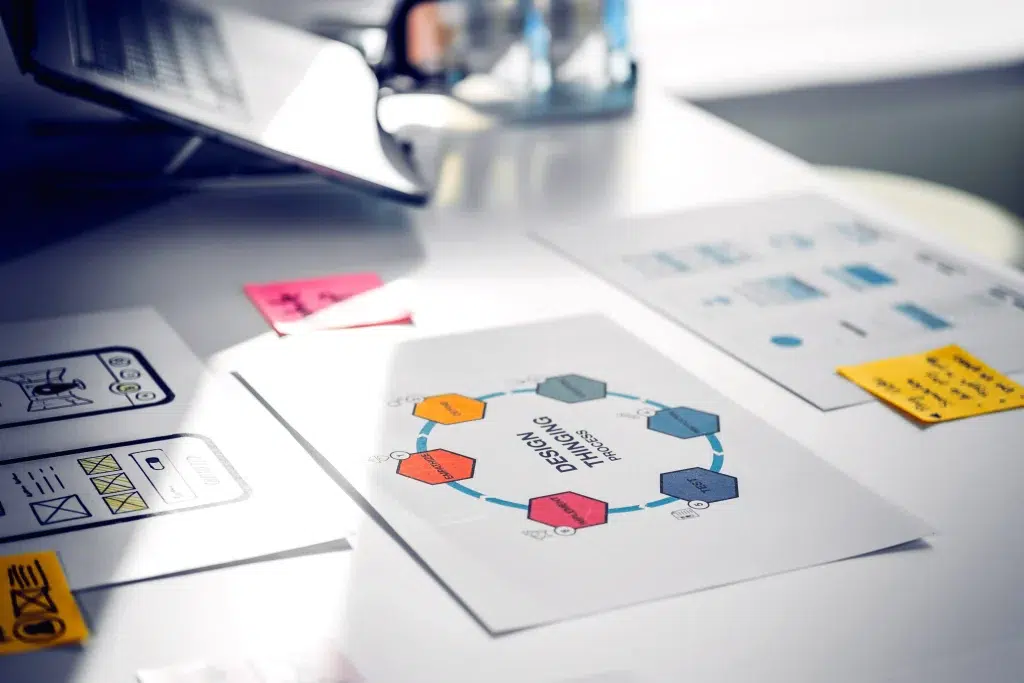 Documentos de trabajo sobre una mesa con diagramas de procesos y diseño UX.